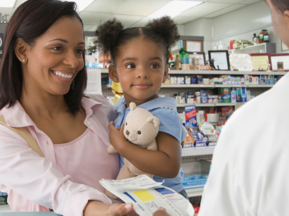 A mother and her young daughter pick up a prescription at the pharmacy. 