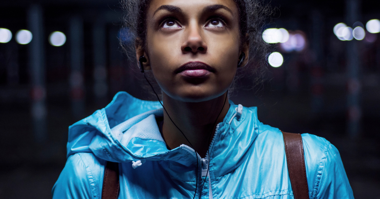A young black woman in a bright jacket looks up