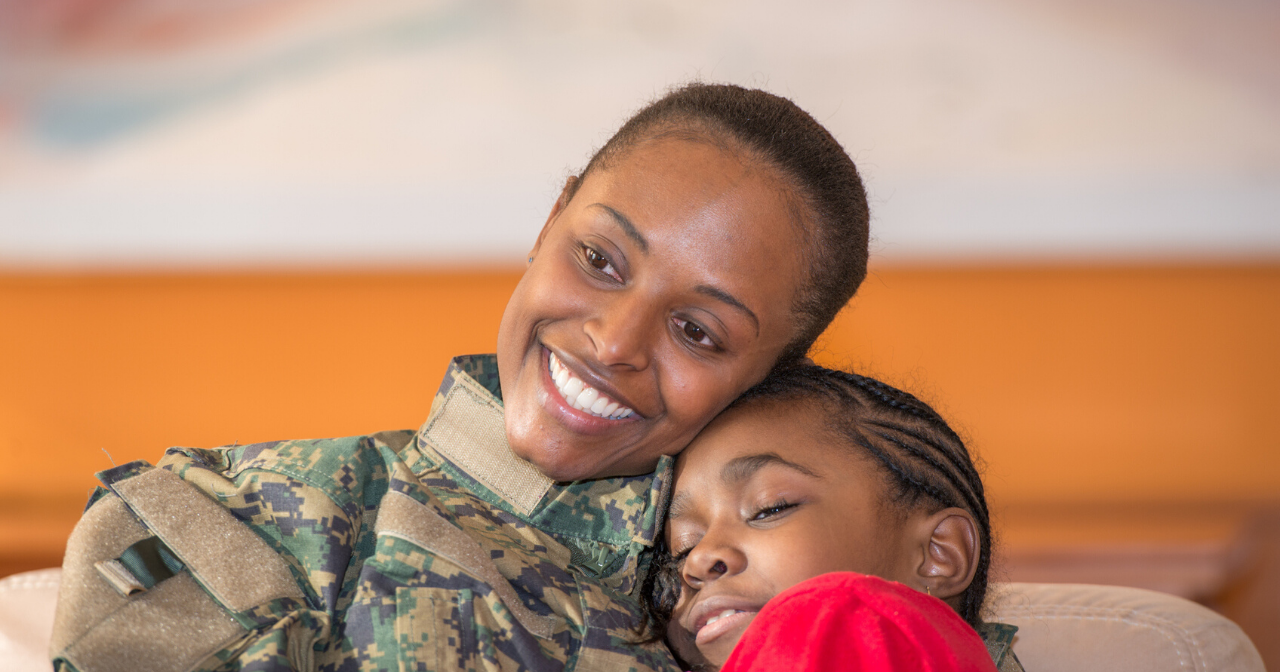 A black woman in a military uniform hugs her daughter. 