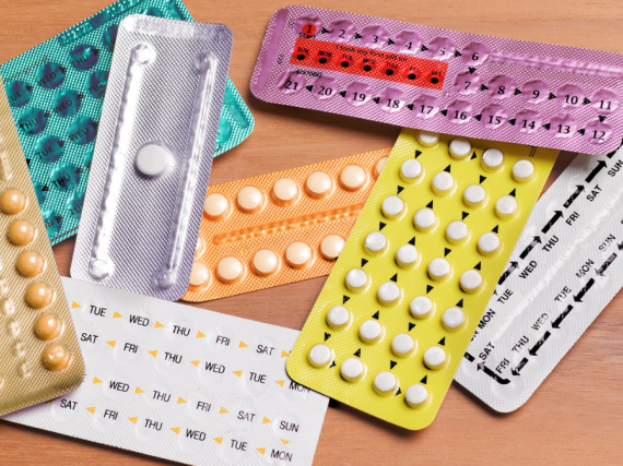 A pile of birth control pill packs on a desk. 