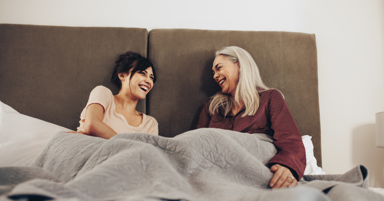 A mother and daughter in bed, talking