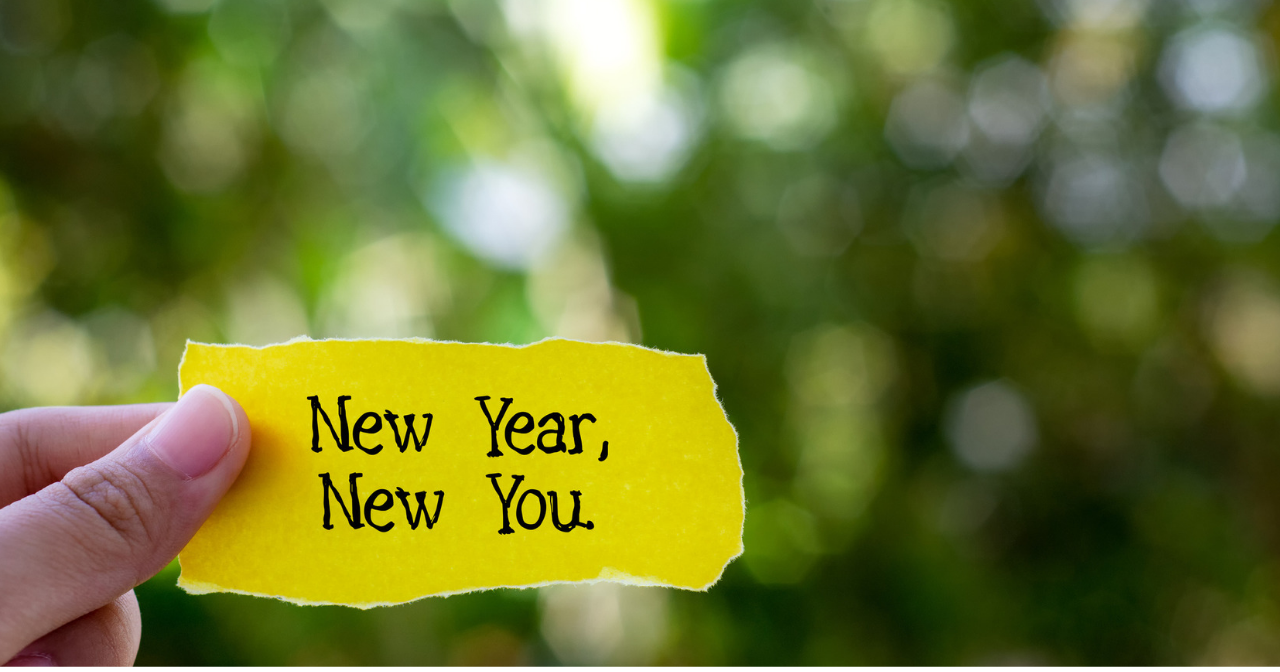 A hand holds a piece of paper that reads, "New year, New you."