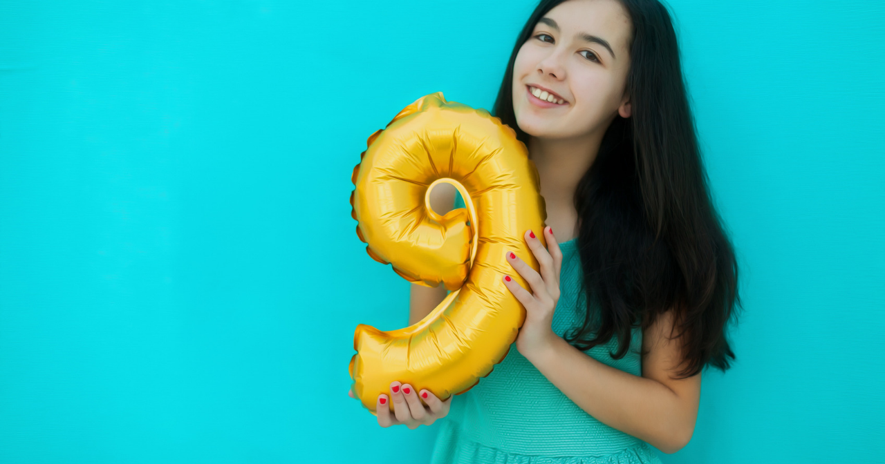 a girl holding a balloon with the number nine