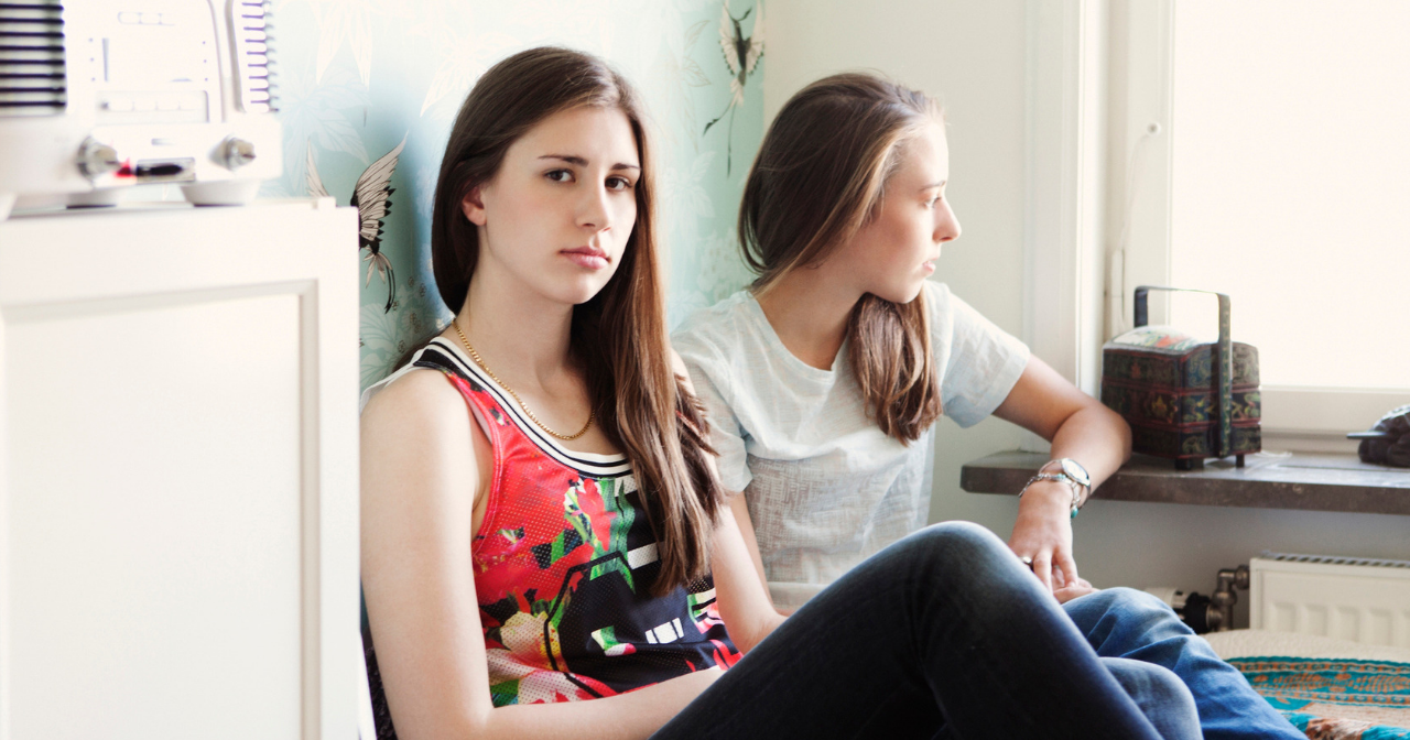Two frustrated teens sitting on a bed