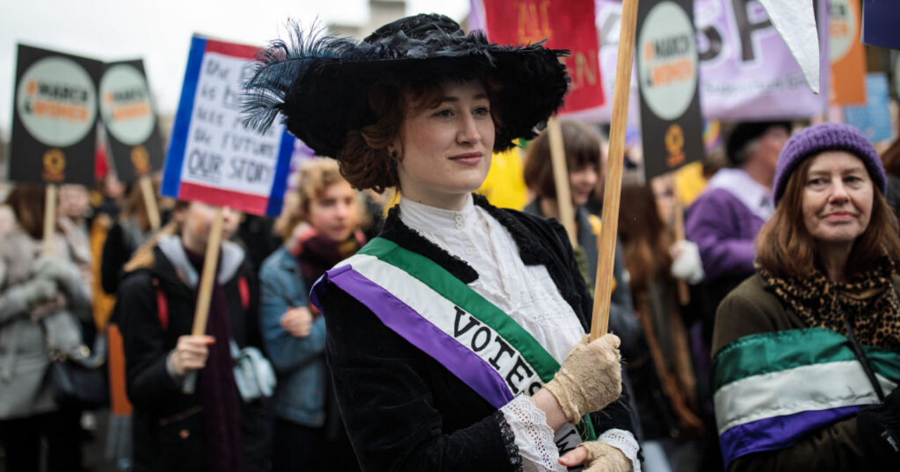 A woman dresses up as a suffragist at a modern-day protest parade. 
