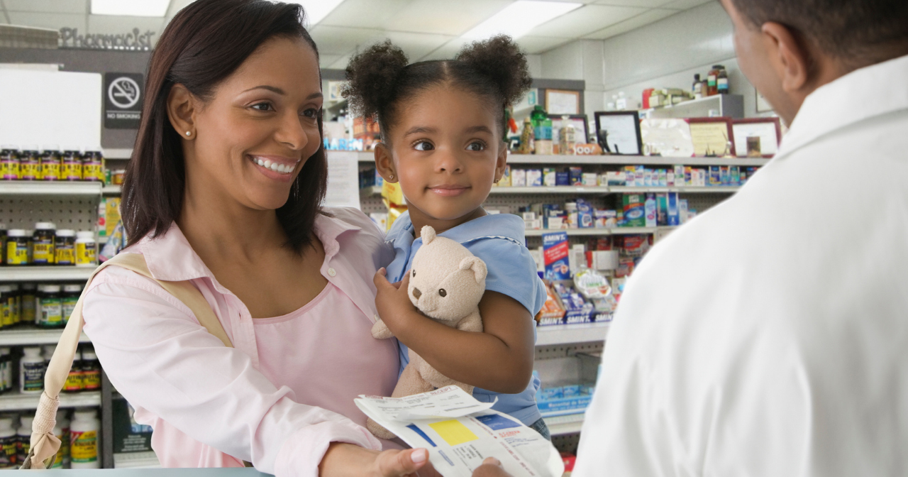 A mother and her young daughter pick up a prescription at the pharmacy. 