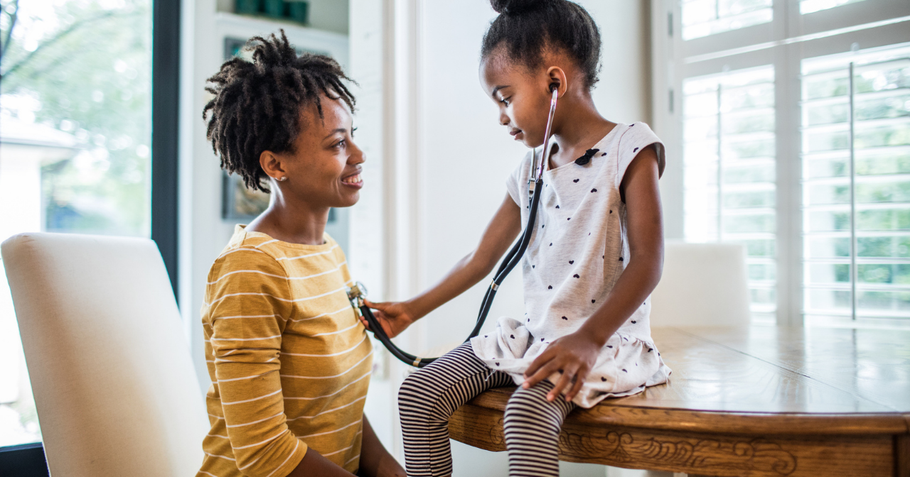 A Black woman and her daughter explore with a stethoscope. 
