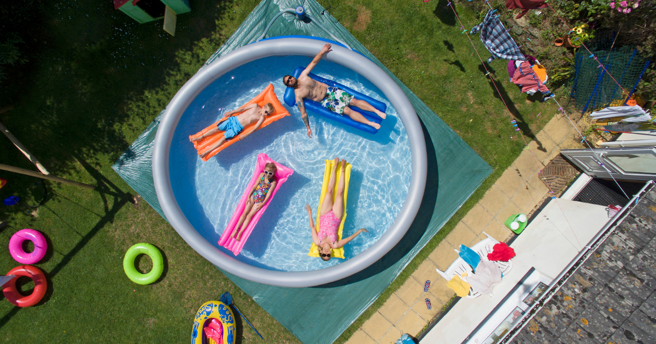 A family of four relaxes on floats in an inflatable pool in the backyard. 