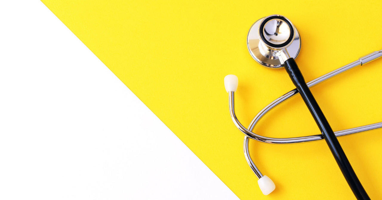 A stethoscope sits on a yellow and white background. 