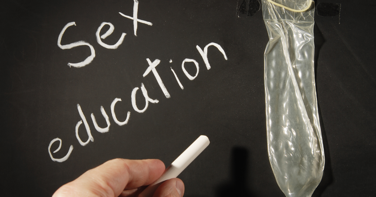 A chalkboard with the words sex education and a condom. 