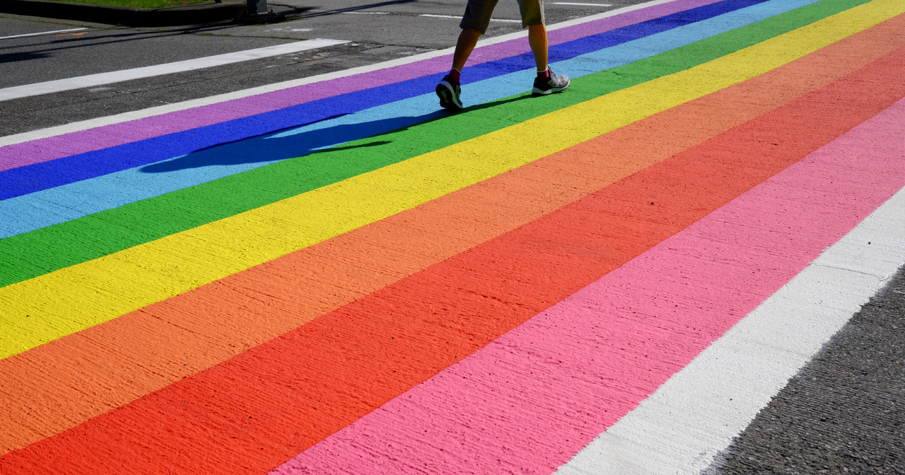 A photo of a crosswalk painted in rainbow stipes. 