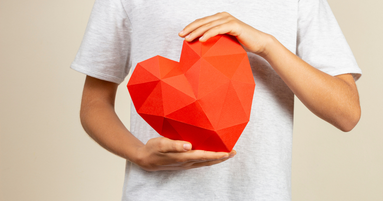 A photo of hands holding a large origami heart. 