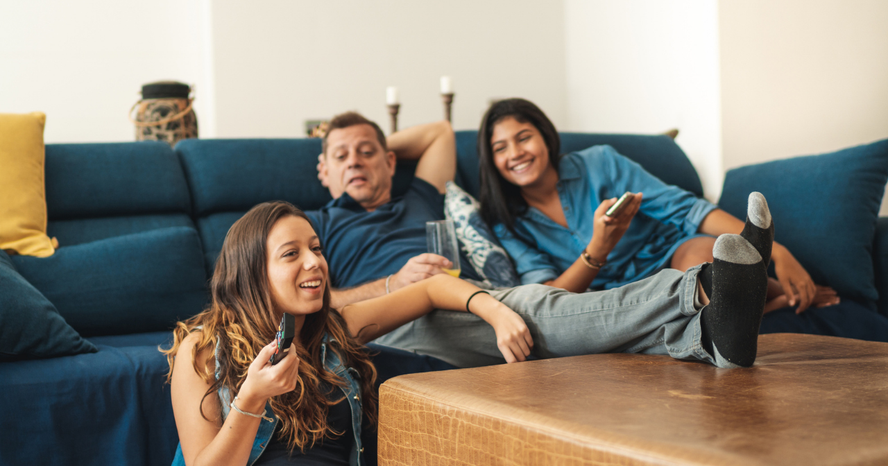 A family of three sits on the sofa and debates what to watch on TV. 