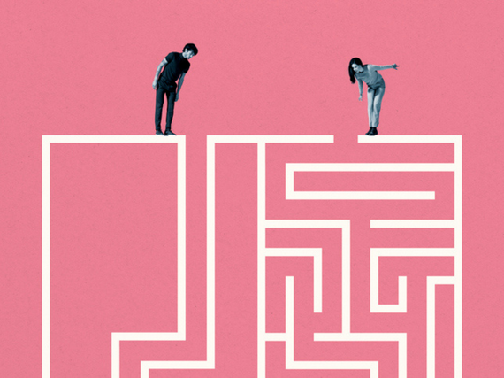 A man and a woman stand on top of a maze and look down. 