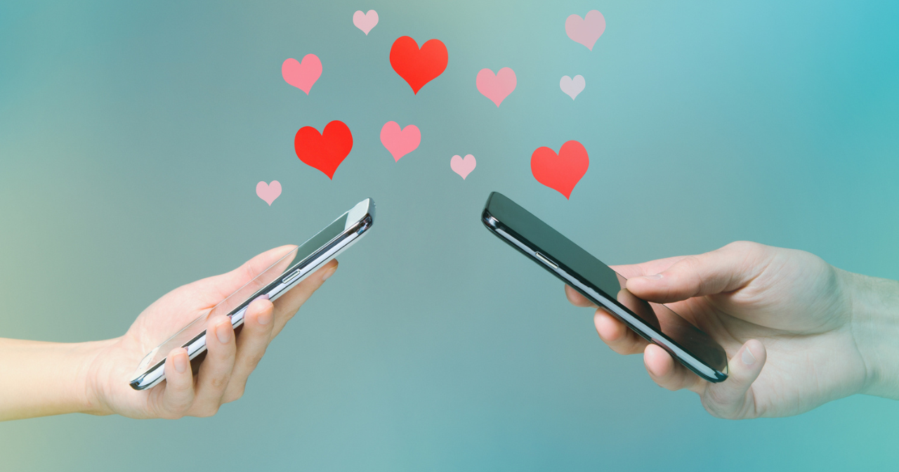 Two hands holding cell phones with hearts flowing between them.