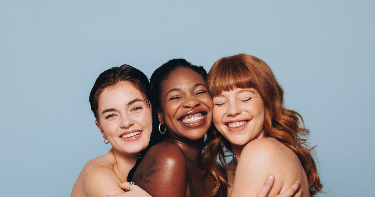 Three woman smile for the camera while hugging each other.