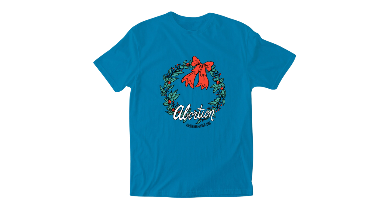 An image of a tshirt with a Christmas wreath with the words, "Abortion. AbortionFinder.org" along the bottom.