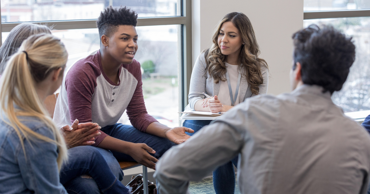 A group of teens sit in a focus group and talk. 