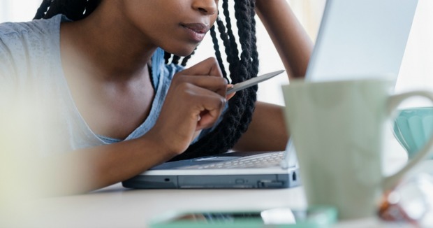 A woman sits at a computer looking concerned. 