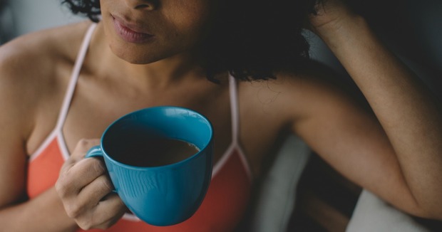 A woman holds a cup of coffee and contemplates 