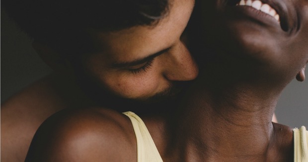 A man kisses a women's neck