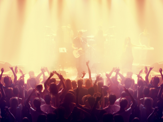 An image of a concert and the audience with their hands up