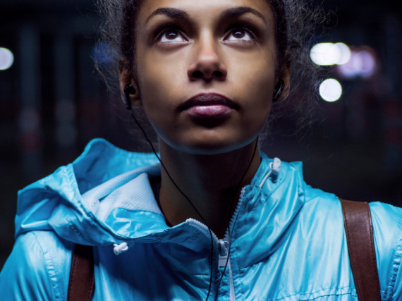 A young black woman in a bright jacket looks up
