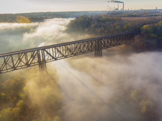 A photo of a bridge in Appalachian Kentucky surrounded by fog with sun beams peaking through. 