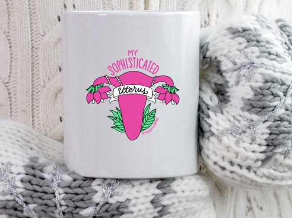 A photo of a pair of mittened hands holding a mug that says, "My sophisticated uterus"