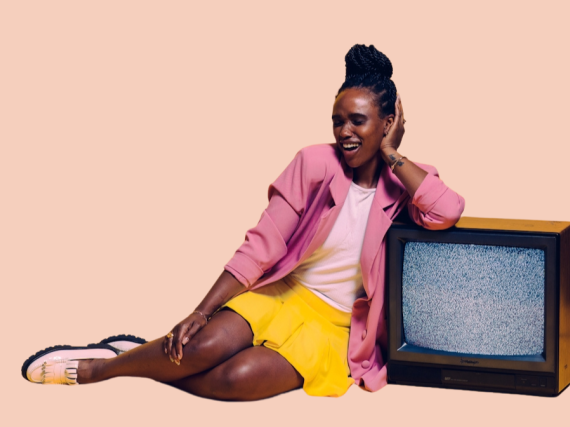 A Black woman leans against a TV and smiles. 