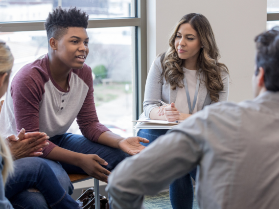 A group of teens sit in a focus group and talk. 