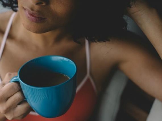 A woman holds a cup of coffee and contemplates 