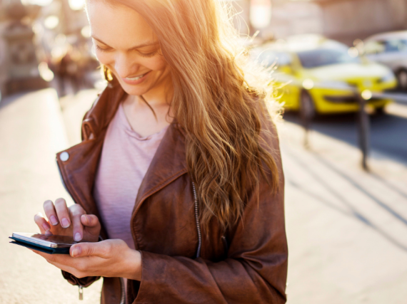 A woman smiles down at her phone