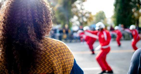 A young Black woman watches a parade pass by celebrating her HBCU.