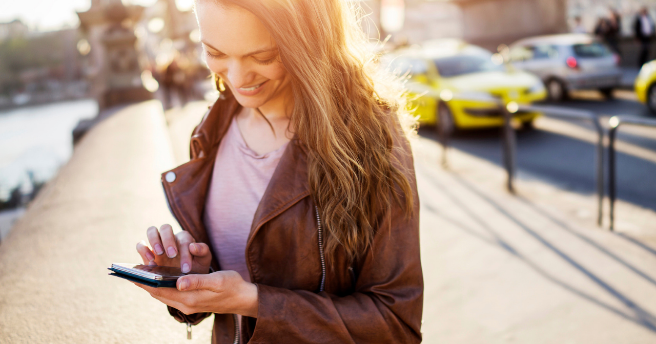 A woman smiles down at her phone